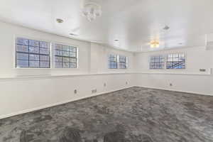 Unfurnished room featuring dark carpet and baseboards