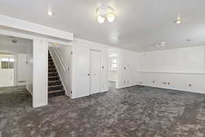 Basement with dark carpet and stairs