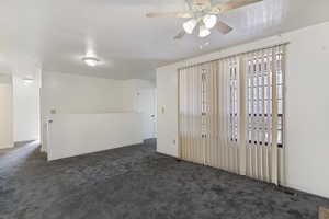 Empty room featuring dark carpet and a ceiling fan