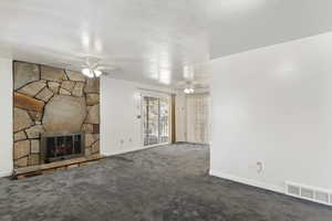 Unfurnished living room with a fireplace, carpet flooring, and a textured ceiling