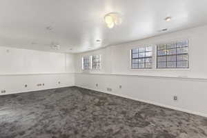 Unfurnished room featuring dark colored carpet and baseboards