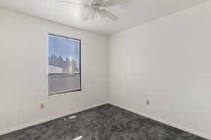 Carpeted spare room featuring baseboards and a ceiling fan