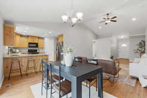 Dining area featuring vaulted ceiling, a chandelier, recessed lighting, light wood-style flooring, and ceiling fan