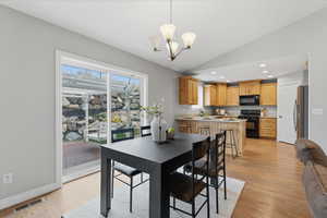 Dining space featuring light wood-type flooring, vaulted ceiling, a chandelier, and recessed lighting