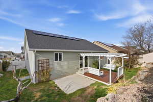 Rear view of house featuring a fenced backyard, roof with shingles, a pergola, roof mounted solar panels, and a wooden deck