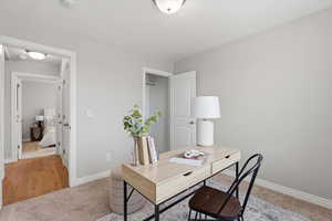 Home office with baseboards and light colored carpet
