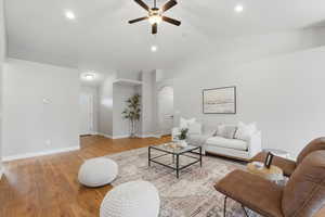 Living area with vaulted ceiling, light wood finished floors, ceiling fan, and recessed lighting