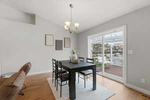 Dining room with light wood-type flooring, vaulted ceiling, and a chandelier
