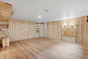Basement featuring wooden walls, wood finished floors, and a textured ceiling
