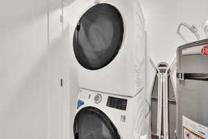 Laundry area featuring water heater and stacked washing machine and dryer