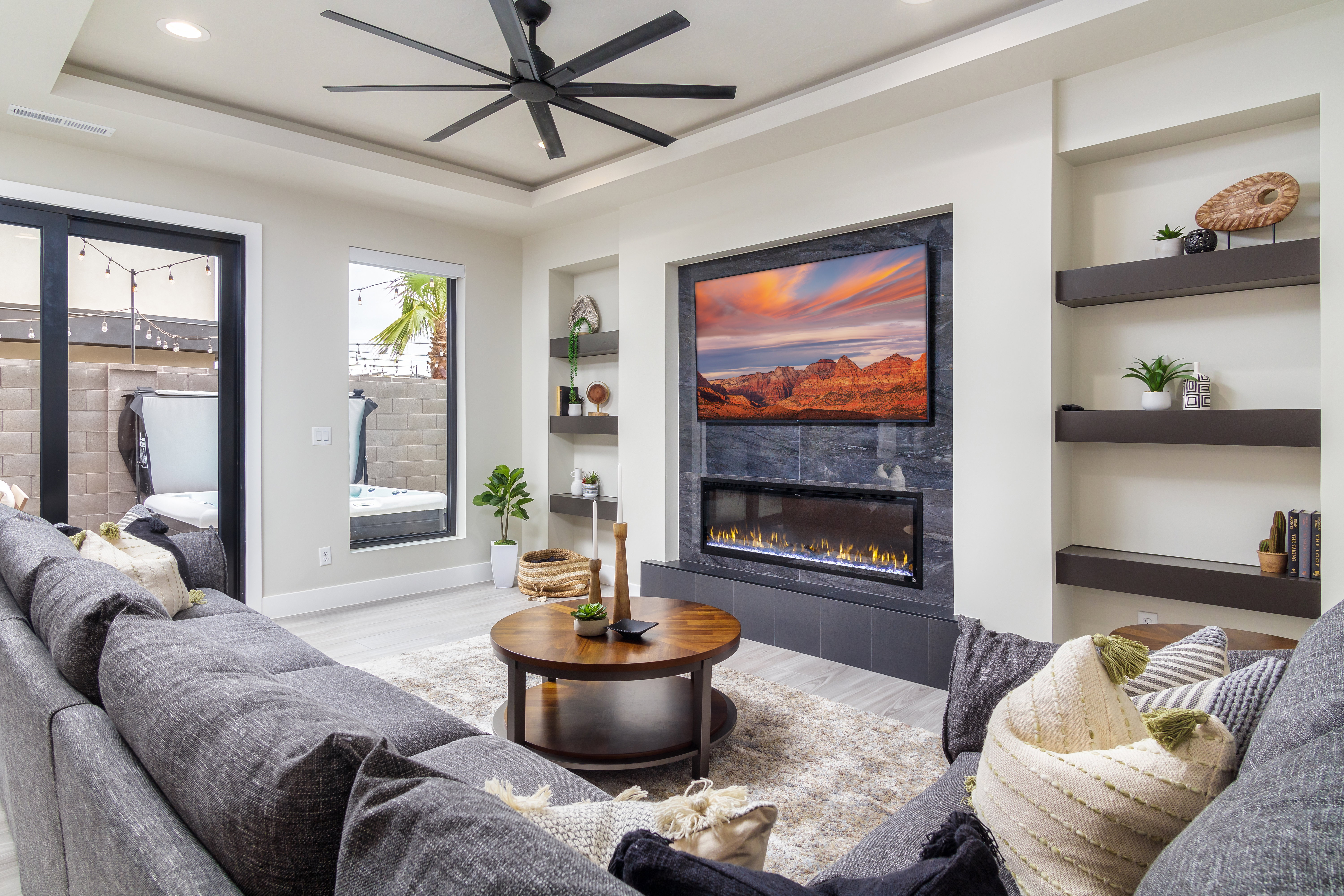 Living room featuring built in features, light wood-type flooring, a tiled fireplace, recessed lighting, and a raised ceiling