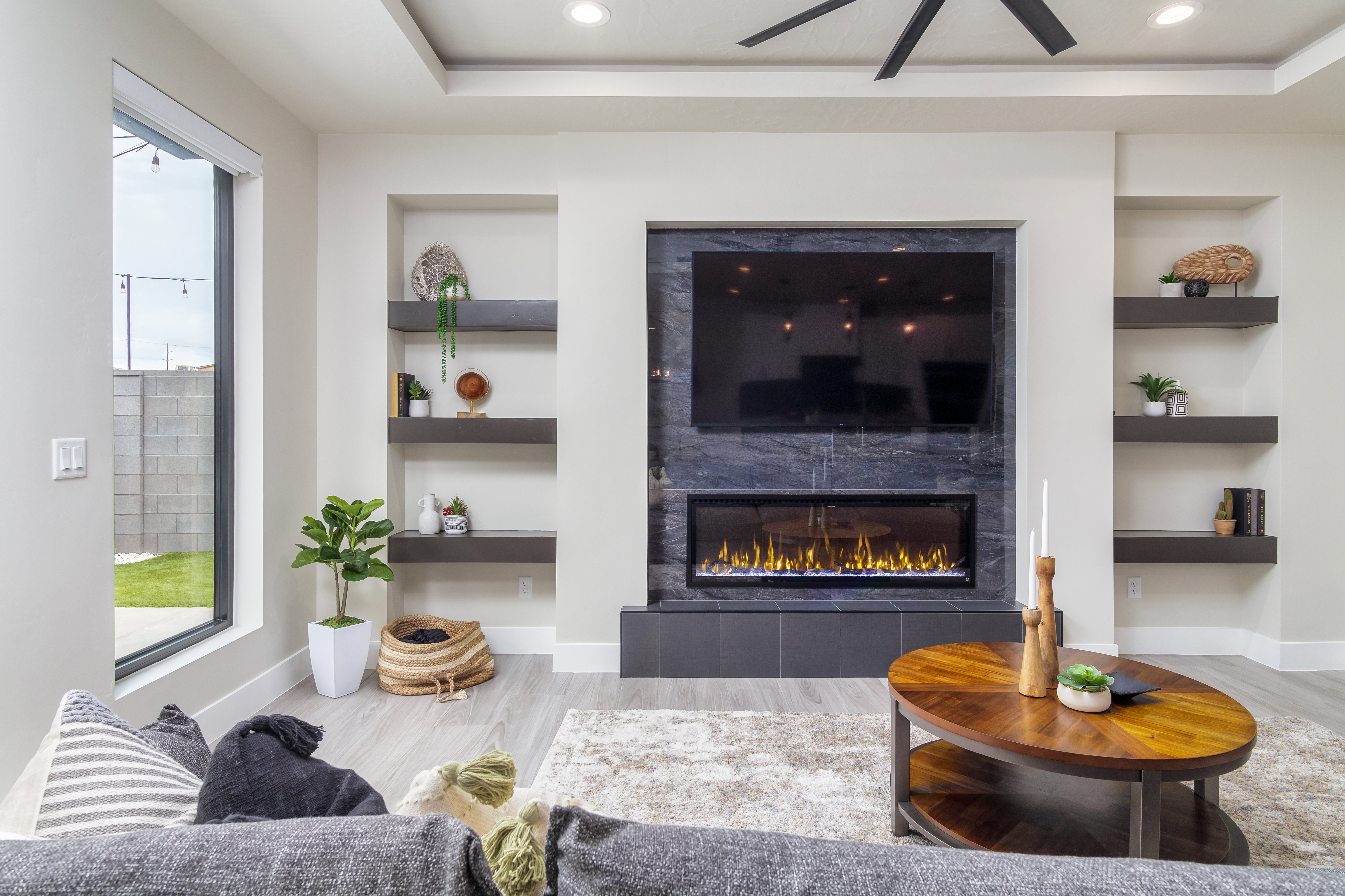 Living area with built in shelves, recessed lighting, light wood finished floors, a fireplace, and a tray ceiling