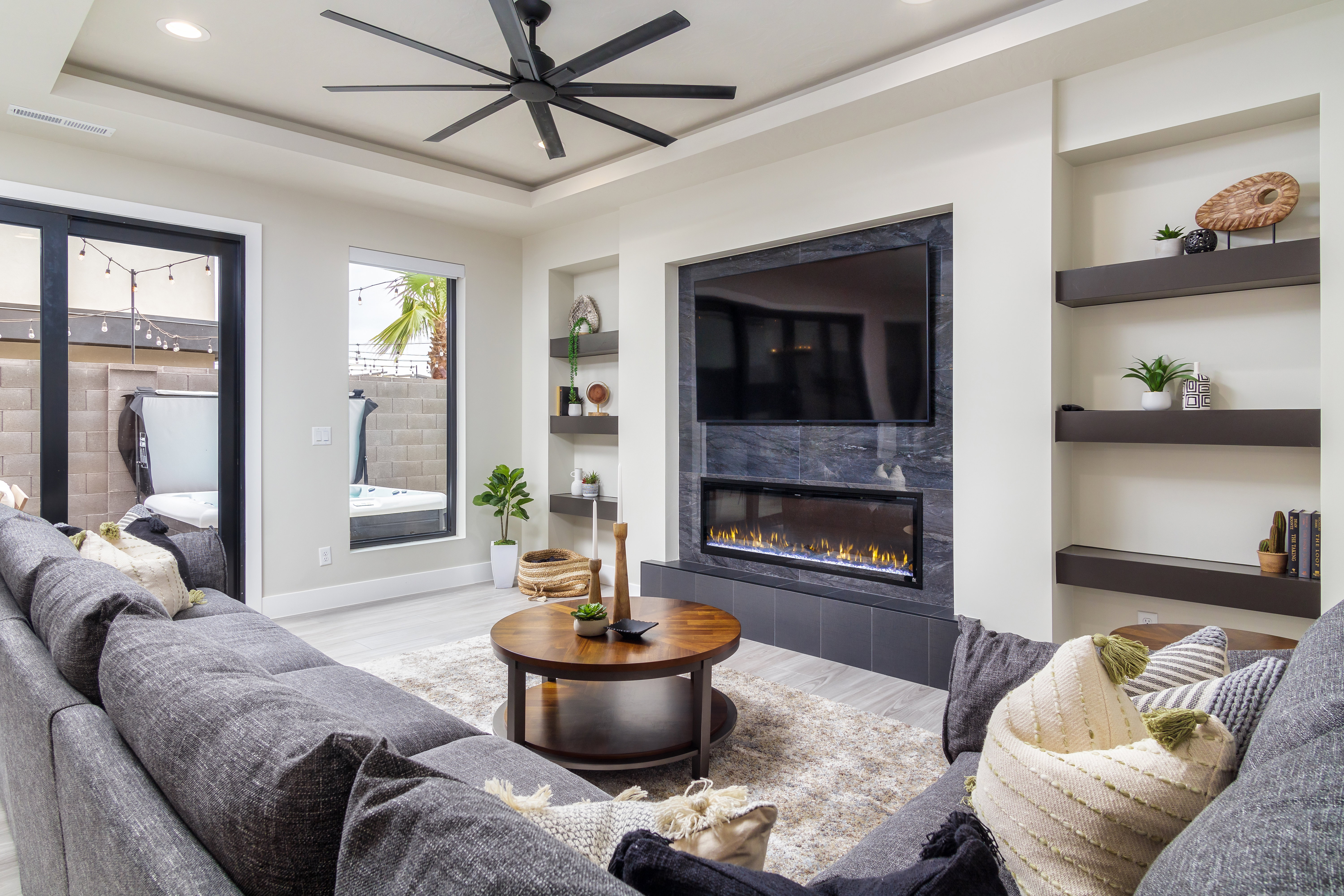 Living room featuring built in shelves, light wood finished floors, a fireplace, a tray ceiling, and recessed lighting