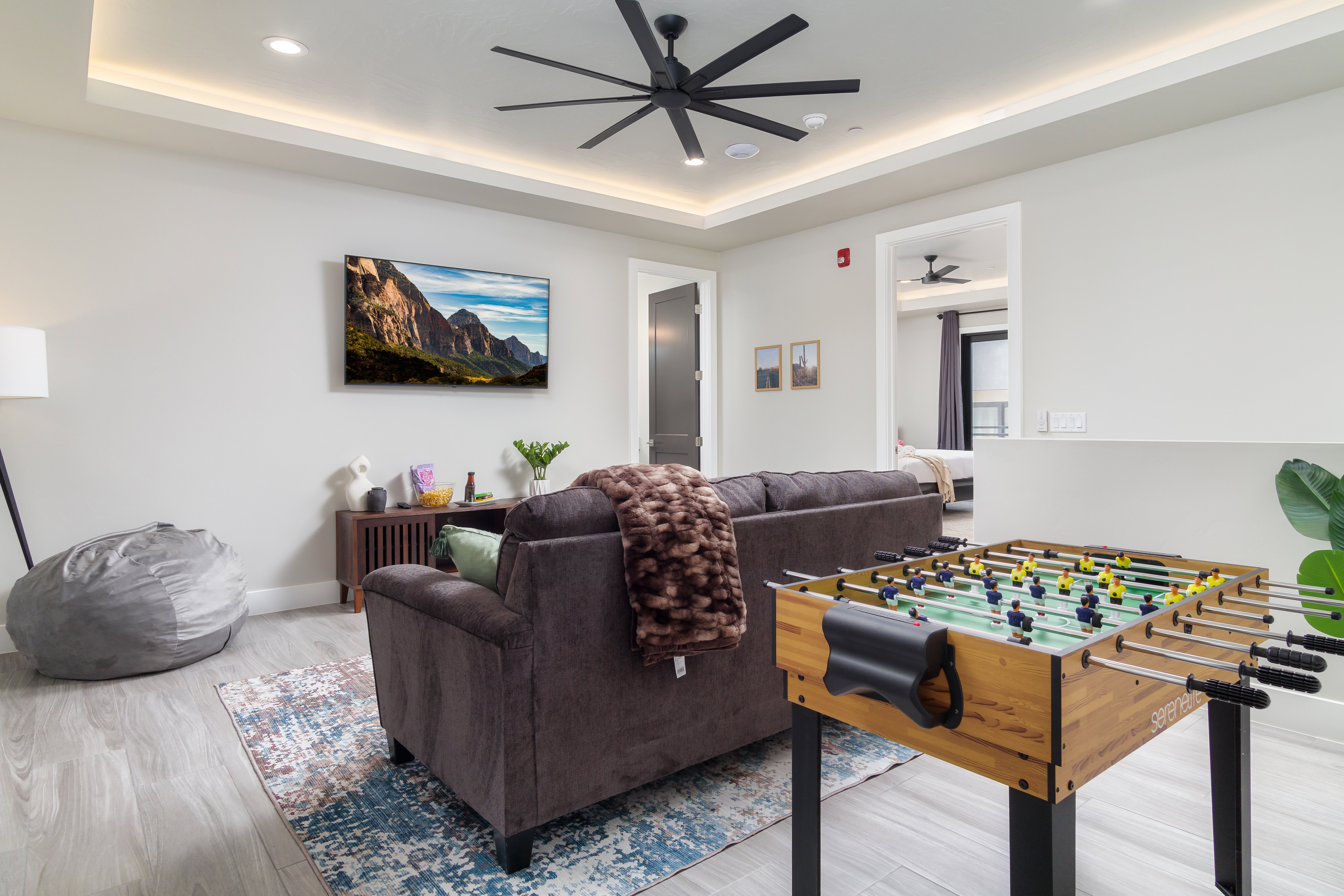 Recreation room featuring a raised ceiling, recessed lighting, ceiling fan, and light wood-type flooring