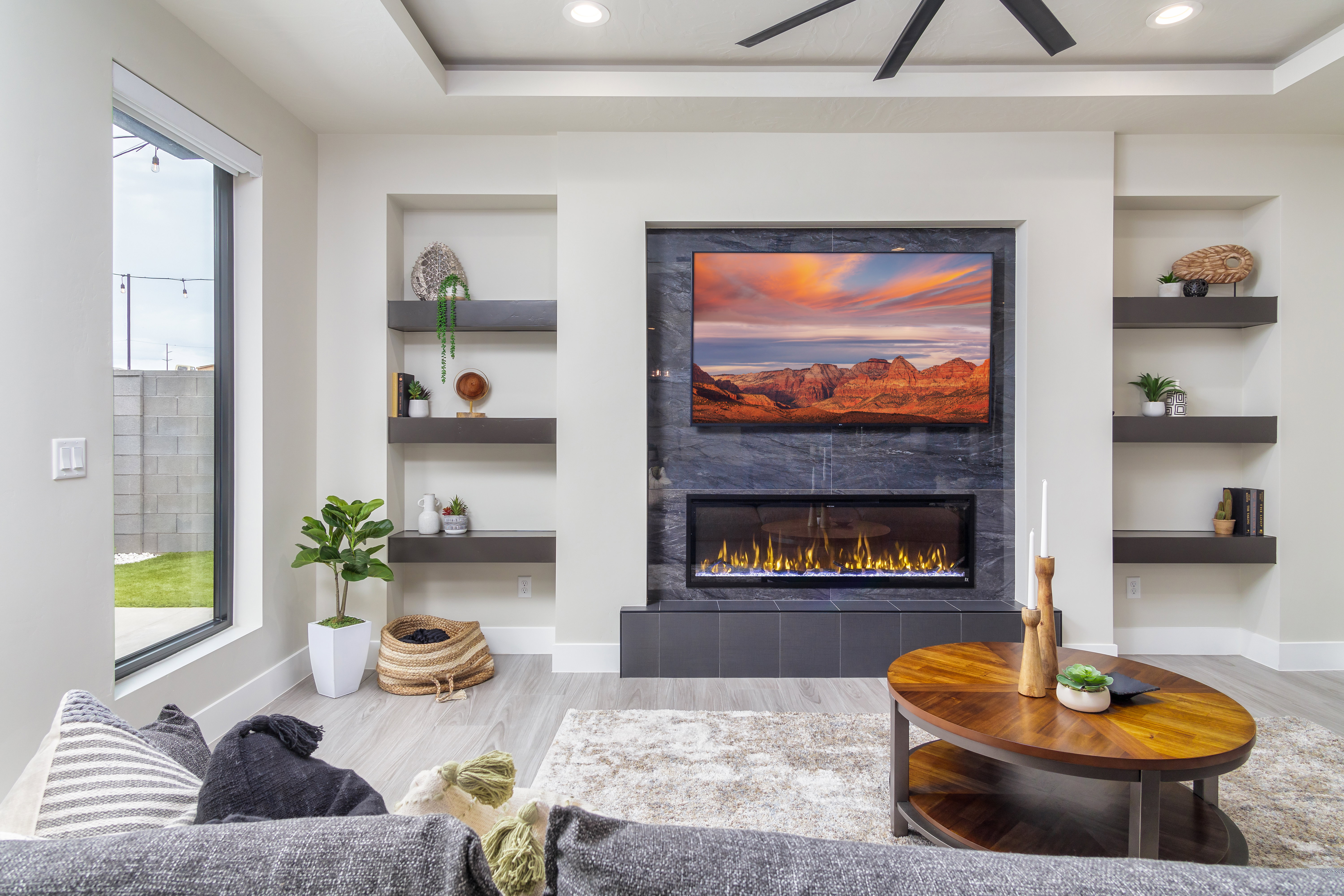 Living room with built in features, recessed lighting, light wood-style flooring, a tile fireplace, and a raised ceiling