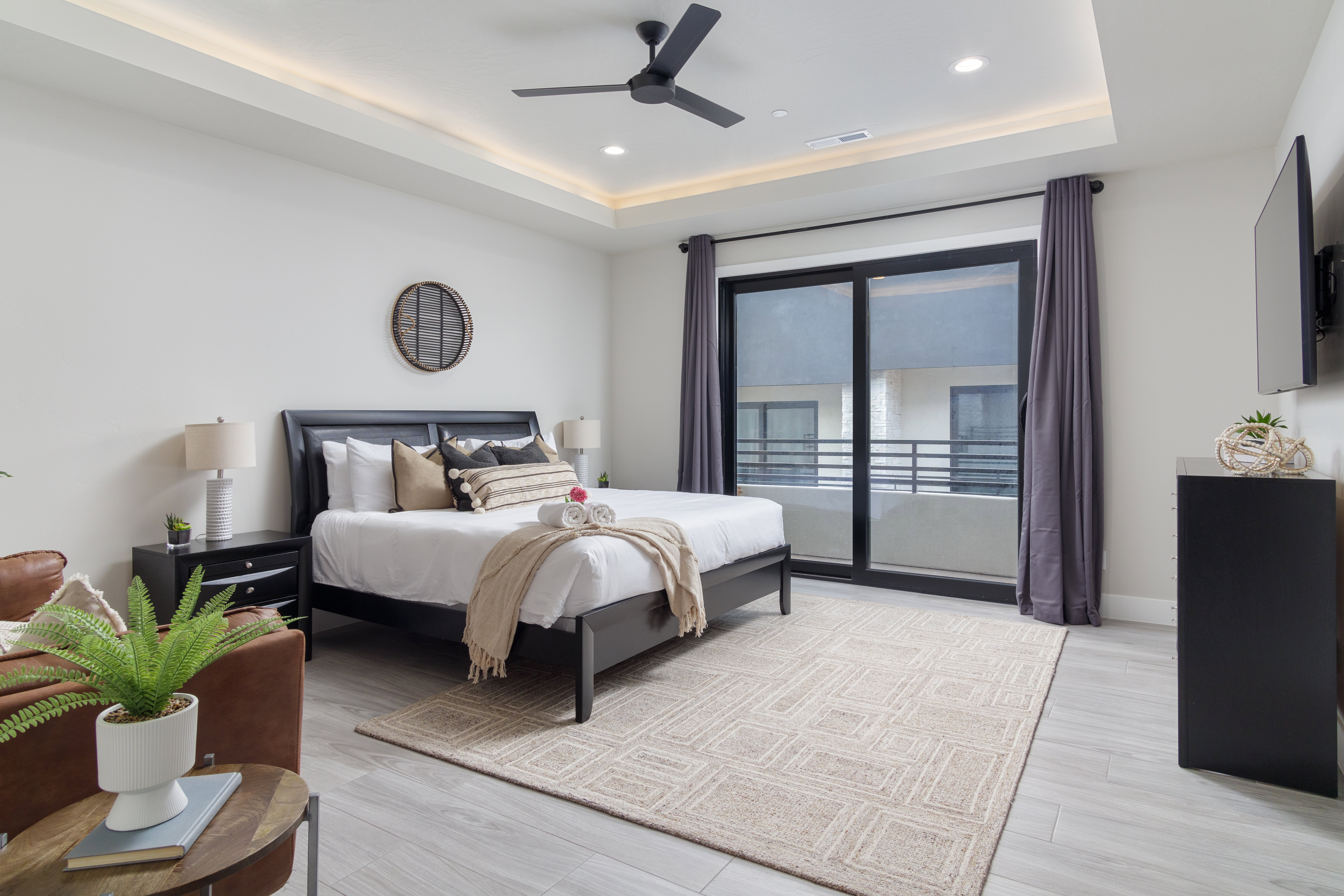 Bedroom with access to outside, a tray ceiling, light wood finished floors, ceiling fan, and recessed lighting