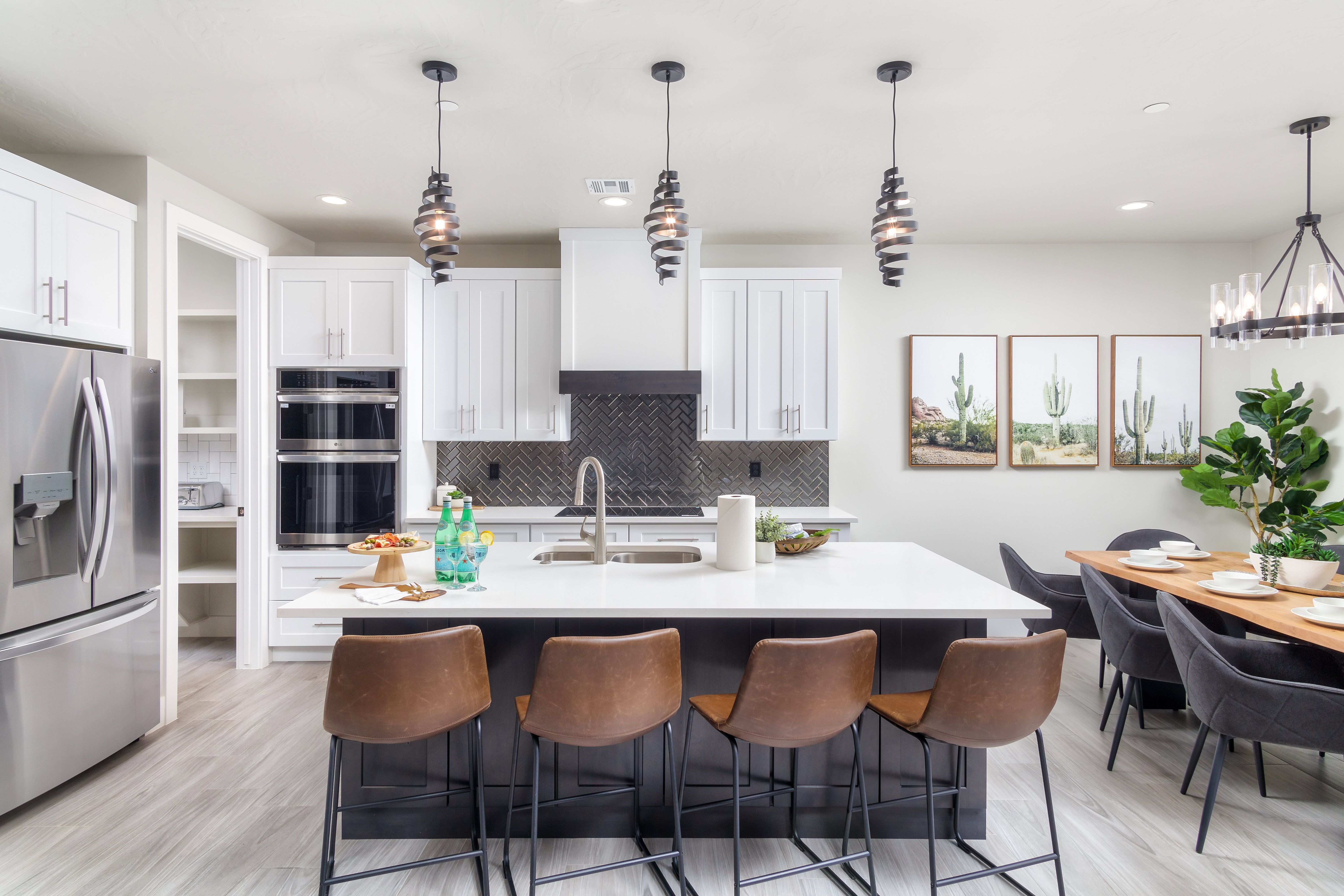 Kitchen featuring decorative light fixtures, stainless steel appliances, white cabinetry, an island with sink, and recessed lighting