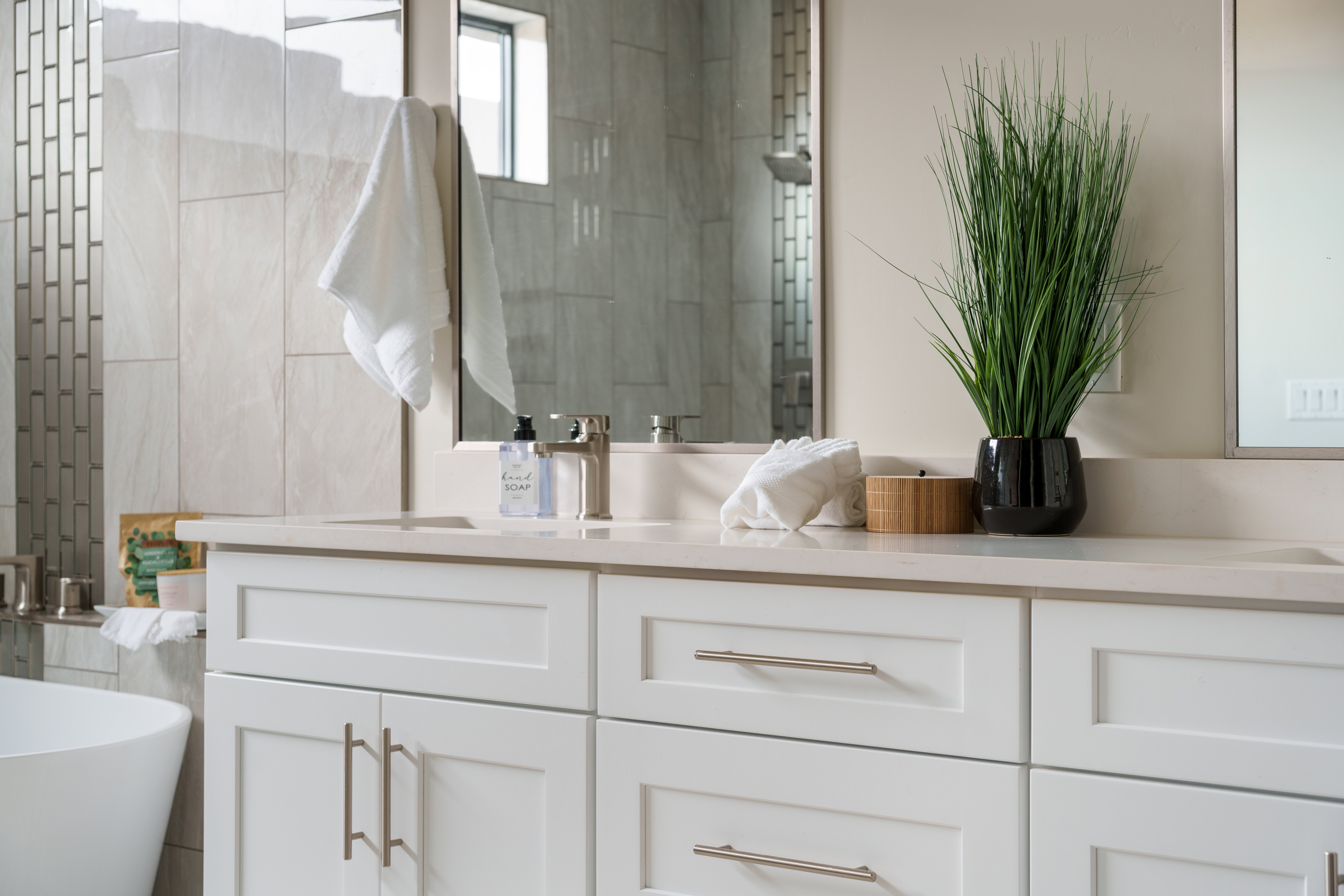 Bathroom featuring double vanity, a soaking tub, and tiled shower