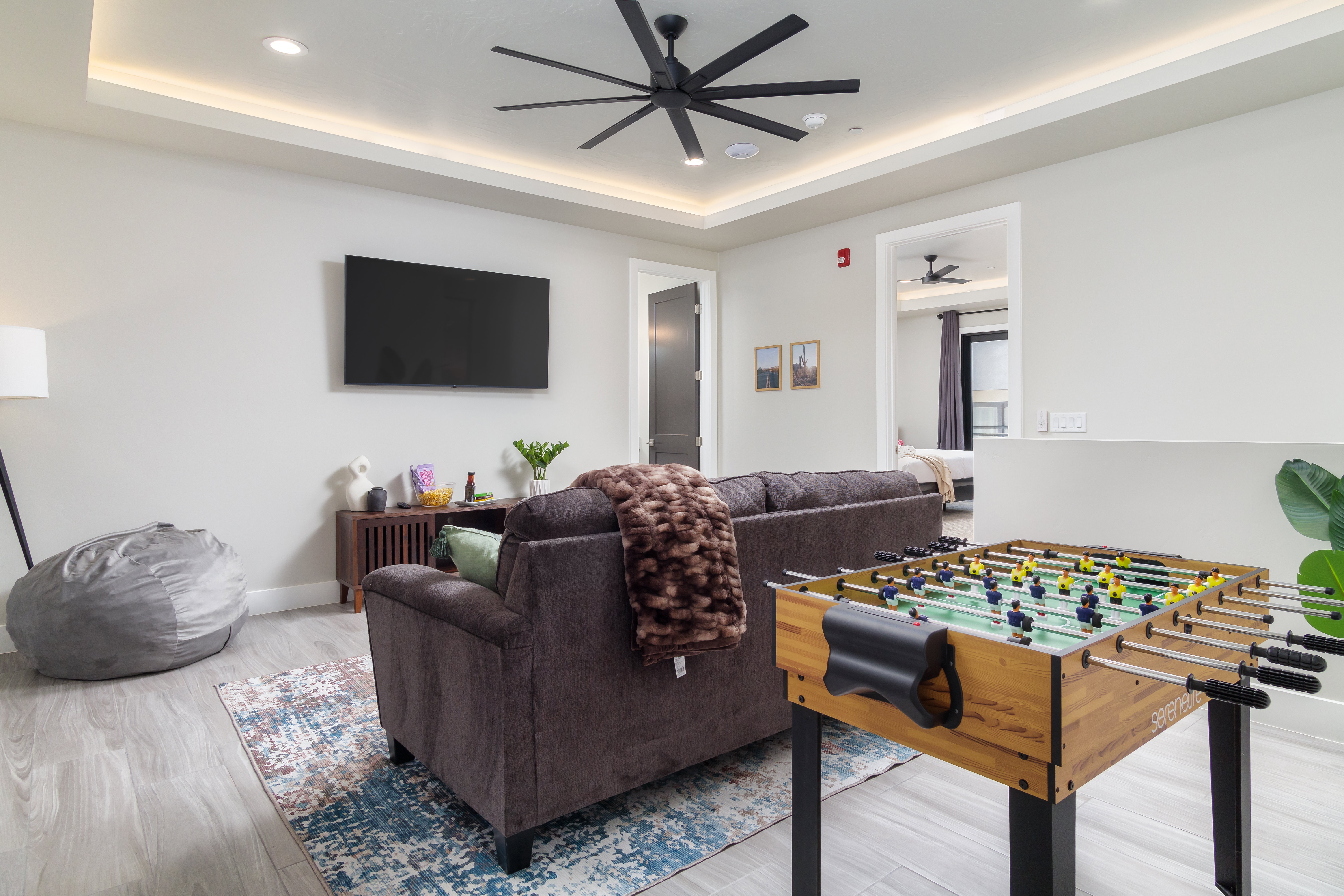 Recreation room with a raised ceiling, recessed lighting, ceiling fan, and light wood finished floors