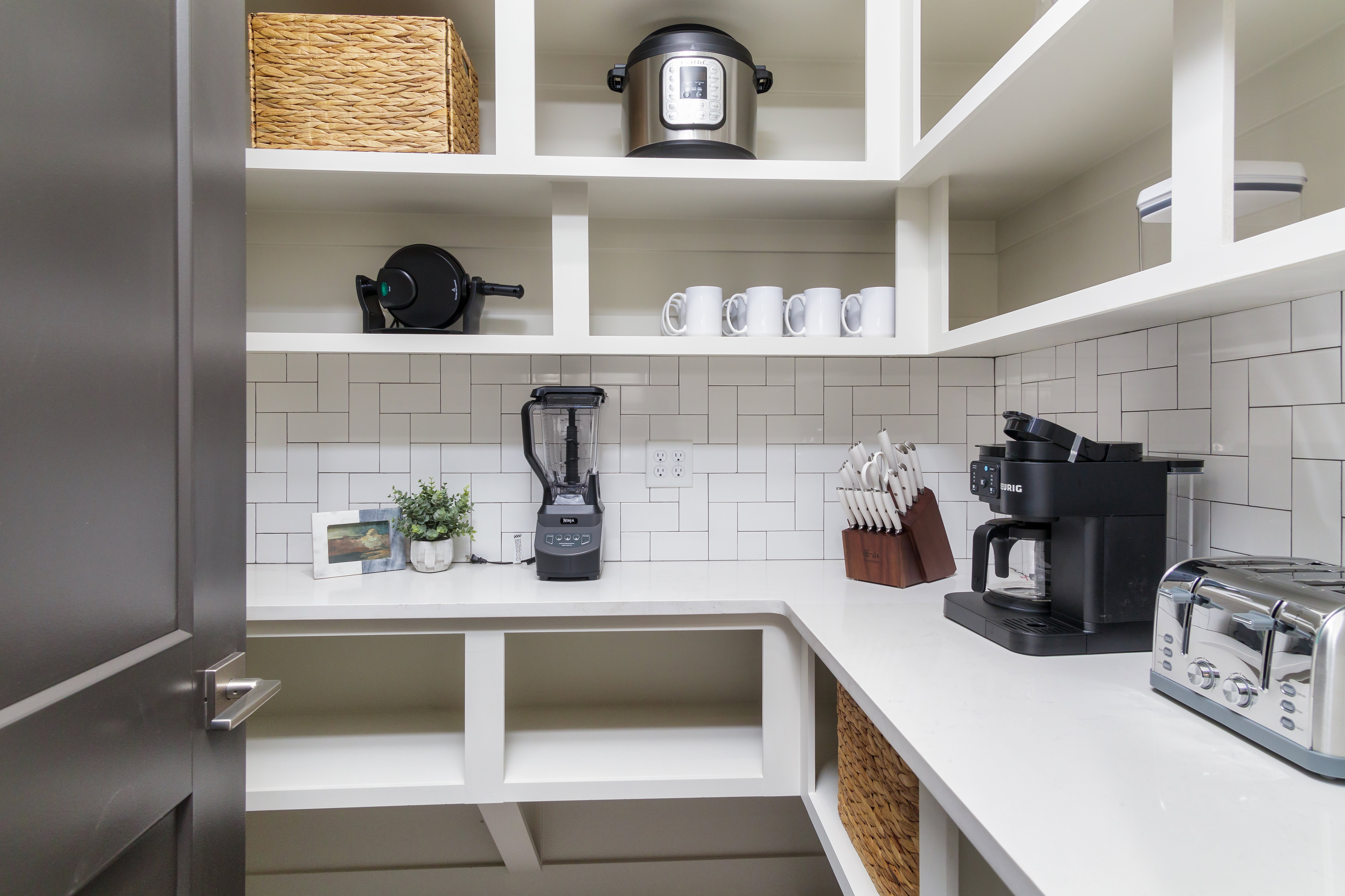 Kitchen view of open shelves, light stone counters, and tasteful backsplash