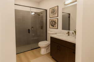 Full bathroom featuring vanity, light wood-style flooring, and a stall shower