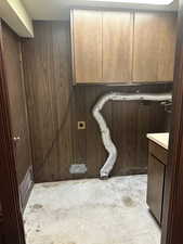 Laundry with vanity and wood walls
