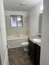 Full bathroom featuring vanity, bathing tub / shower combination, a textured ceiling, and stone finish floors