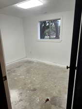 Empty room with a textured ceiling and concrete flooring