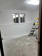 Spare room with unfinished concrete floors and a textured ceiling