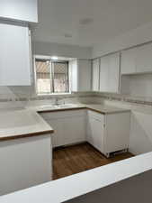 Kitchen featuring white cabinetry, dark wood-type flooring, light countertops, and backsplash