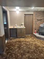 Bar featuring light countertops, a wood stove, a textured ceiling, and dark brown cabinetry