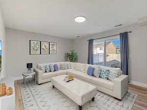 *THIS PHOTO IS VIRTUALLY STAGED TO SHOW POSSIBLE FURNITURE CONFIGURATIONS* Living area featuring baseboards and wood finished floors