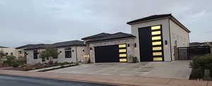 View of front of property featuring stone siding, an attached garage and RV garage, stucco siding, and spacious driveway