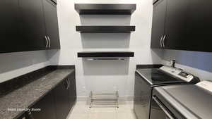 Washroom with cabinet space, washing machine and clothes dryer, and light tile patterned floors