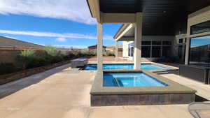 View of pool featuring a fenced backyard, a patio area, and a pool with connected hot tub