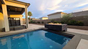 View of swimming pool featuring an outdoor fire pit, a patio area, a fenced backyard, and an in-ground hot tub