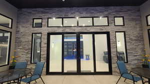 Back of house with french doors, a patio, and outdoor dining space and rock wall