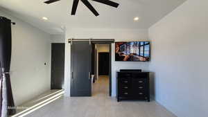 Primary bedroom featuring a barn door, recessed lighting, a ceiling fan, a textured ceiling, and light tile patterned floors
