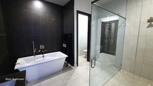 Primary Bathroom with a shower stall, tile walls, a freestanding tub, and light tile patterned flooring