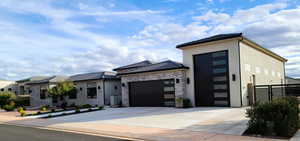 View of front of home with an attached garage, concrete driveway, stucco siding, and stone siding