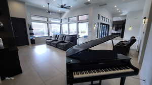 Living room featuring light tile patterned flooring, recessed lighting, a towering ceiling, and a ceiling fan