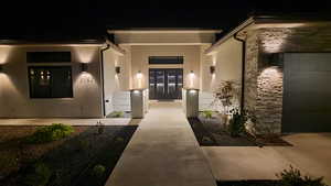 Exterior entry at night with stone siding and stucco siding