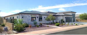 View of front of house featuring stucco siding, driveway, a garage, and stone siding