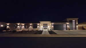 View of front of house with a garage, stone siding, concrete driveway, and stucco siding