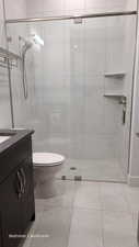 Bathroom1 featuring a shower stall, light tile patterned flooring, and vanity and walk in closet