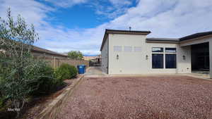 Back of house with stucco siding and side yard parking space
