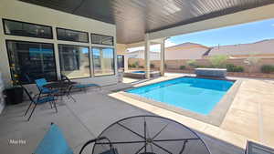 View of pool featuring a patio, a fenced backyard, outdoor dining area, and a pool with connected hot tub