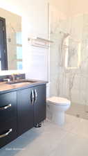 Full bath featuring vanity and a marble finish shower