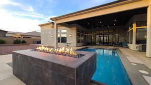 View of swimming pool with an outdoor fire pit and a patio area
