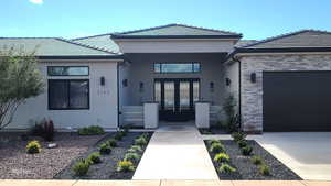 Entrance to property with stucco siding, a tile roof, an attached garage, and stone siding